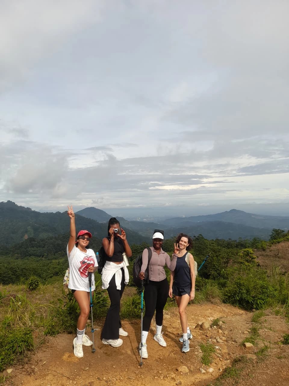 Sepasang kekasih menikmati pemandangan perbukitan yang luas dari puncak.