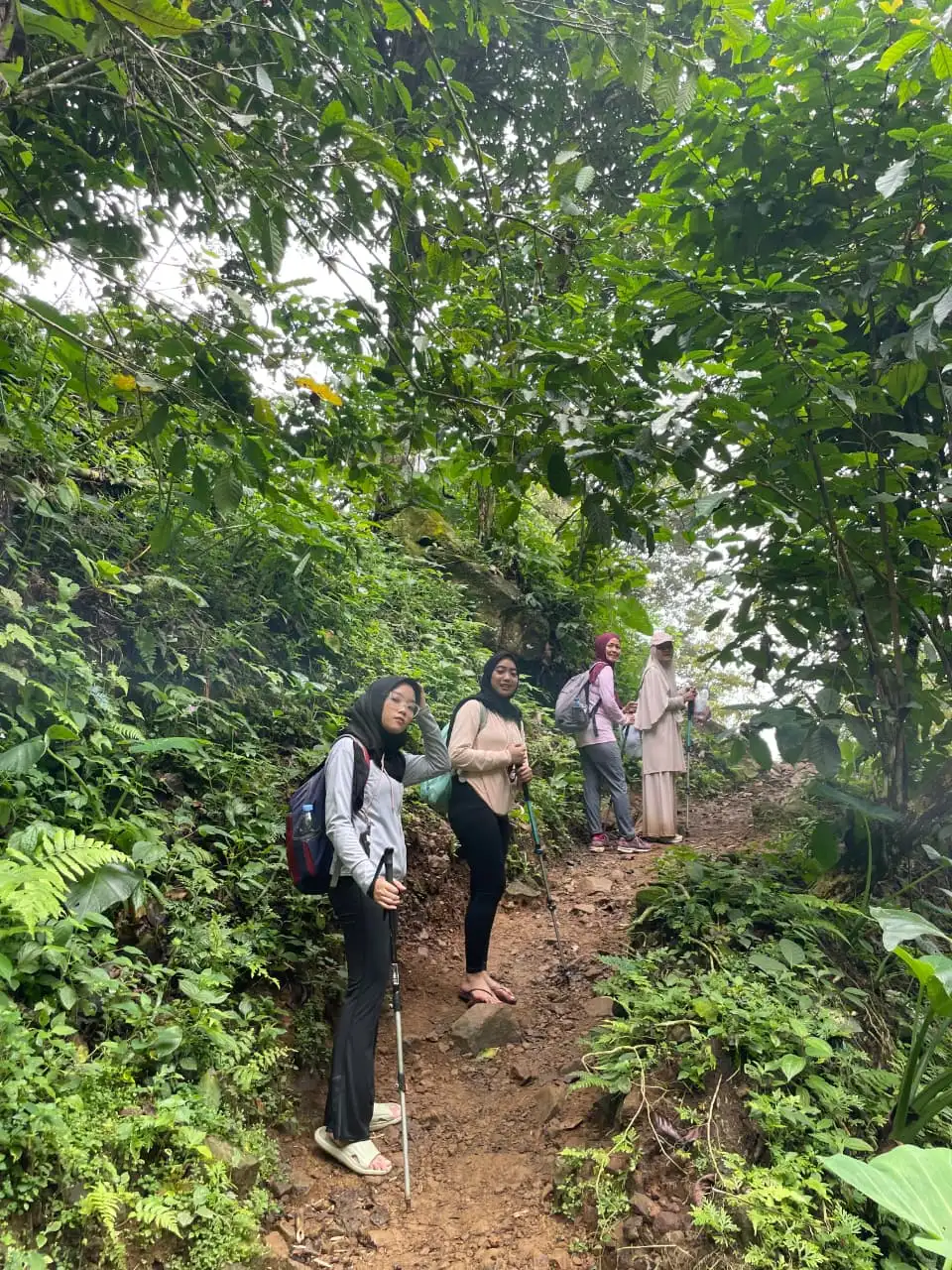 Dua orang peserta menikmati jernihnya air sungai sambil menunjuk ke arah tebing hijau.